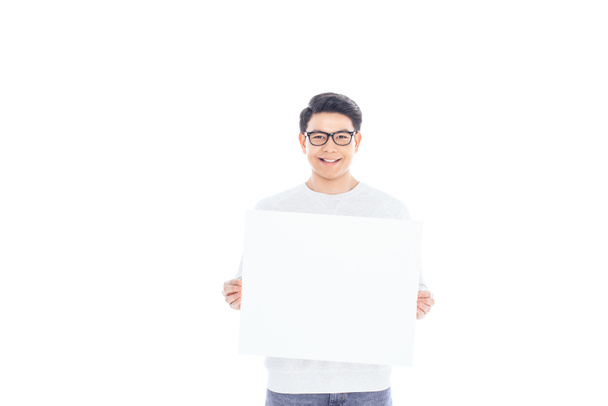portrait of smiling asian teenager with empty banner in hands isolated on white - Foto, afbeelding