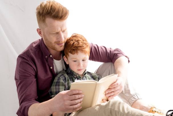 redhead father and son reading book together at home - Photo, Image