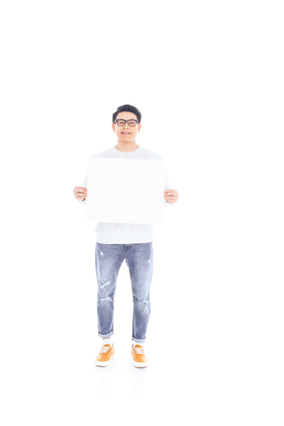 smiling asian teenager with empty banner in hands isolated on white - Foto, Imagen