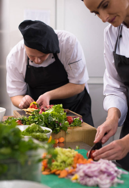 Professional team cooks and chefs preparing meals at busy hotel or restaurant  kitchen - Valokuva, kuva