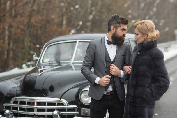 Escort of girl by security. Couple in love on romantic date. Bearded man and sexy woman in fur coat. Retro collection car and auto repair by mechanic driver. Travel and business trip or hitch hiking. - Valokuva, kuva