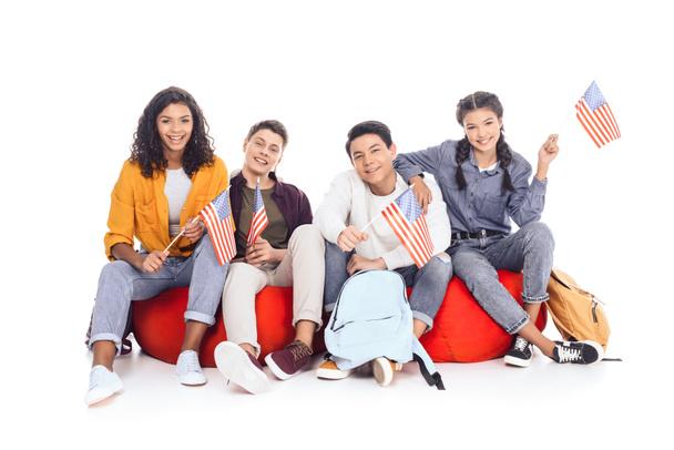 ομάδα εφήβων μαθητών με σημαίες Ηνωμένες Πολιτείες κάθεται στο τσάντες φασολιών που απομονώνονται σε λευκό - Φωτογραφία, εικόνα