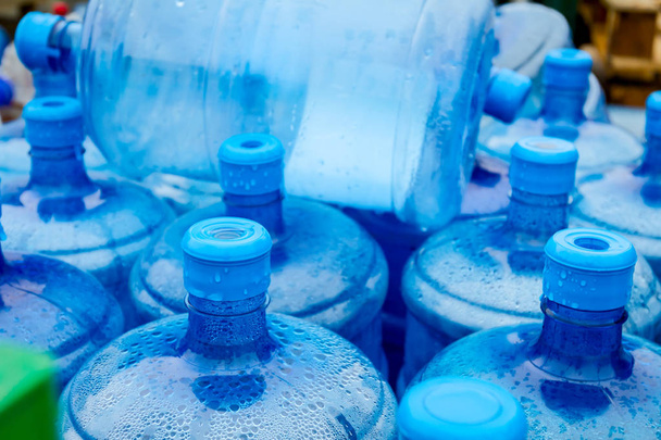 Απέραντο γαλάζιο πόσιμο νερό βαρέλια, μπουκάλια, γαλόνι, παίρνει βραχεί στη βροχή. - Φωτογραφία, εικόνα