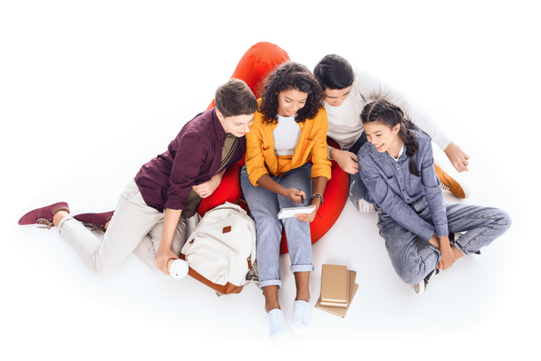 high angle view of group of teen students studying while sitting on bean bag isolated on white - Foto, imagen