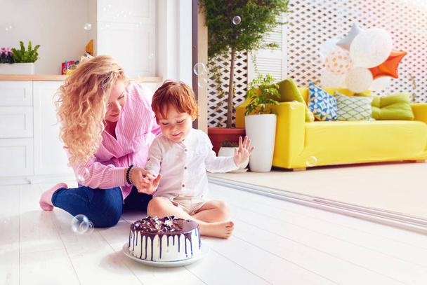 happy mother and toddler son poking fingers in birthday cake - Photo, image