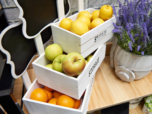 Fruits apples, oranges and lemons in white boxes in store - Fotó, kép