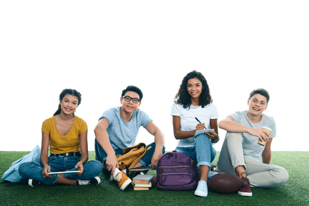 group of teen students studying while sitting on grass isolated on white - Fotoğraf, Görsel