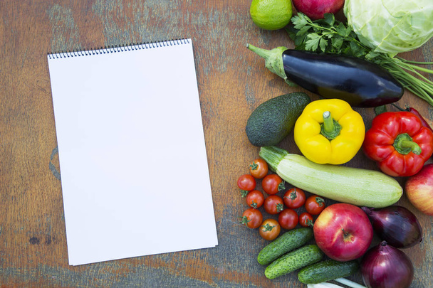 Különböző friss bio zöldségek és gyümölcsök, rusztikus, fából készült háttér és a notebook. Diéta terv. Egészséges étel. Felülnézet. A fenti. - Fotó, kép