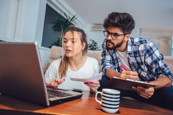Woman and man doing paperwork together, paying taxes online on laptop - Photo, Image