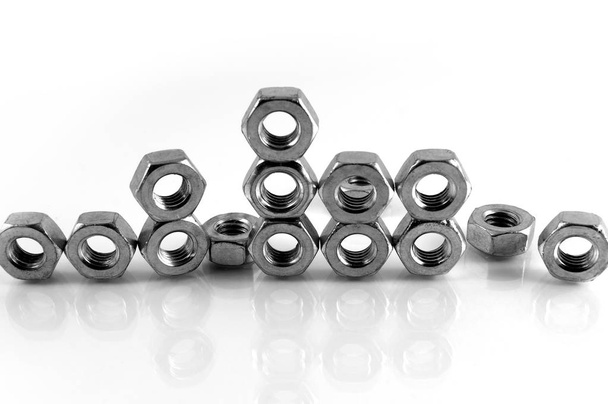 Several metal nuts with internal thread on a white background, laid out in an arbitrary shape. - 写真・画像