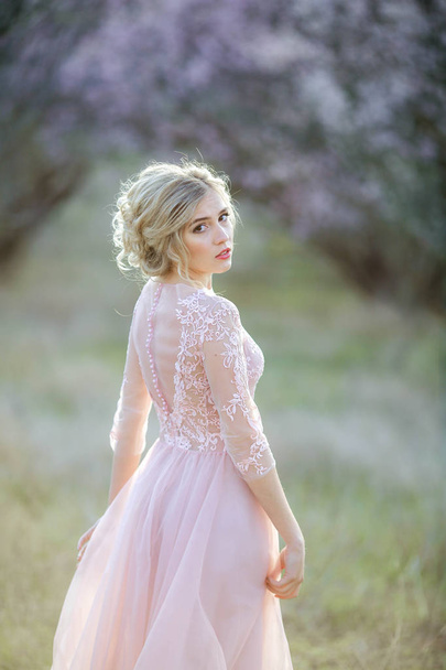 beautiful blonde woman posing in the garden in pink dress  - Foto, imagen