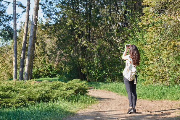 girl with camera taking pictures of nature in spring, beautiful forest and trees on a Sunny day - 写真・画像