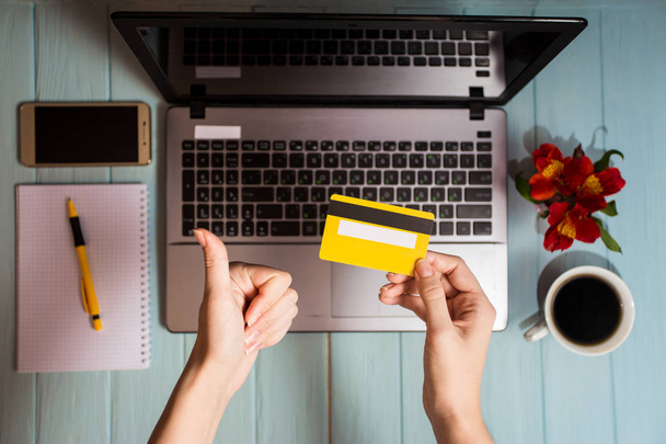 концепція онлайн нових технологій, покупки купують товари. жінка купує з дебетовою кредитною карткою і ноутбуком в кафе. Вид зверху. Плоский прошарок
 - Фото, зображення