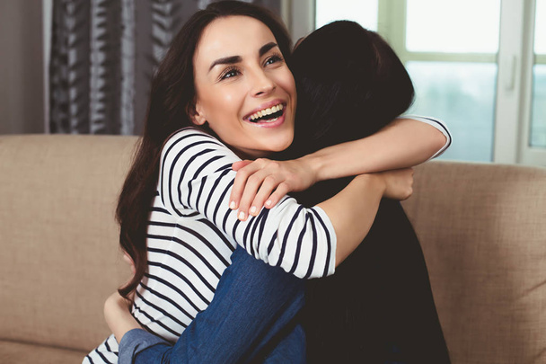 Two beautiful women hug each other and smiling - Фото, зображення