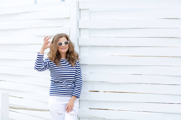 young beautiful woman posing in striped shirt against wooden background - Photo, image