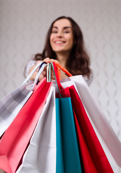 Happy beautiful woman in casual wear with shopping bags in hands looking on camera and smiling - Photo, Image