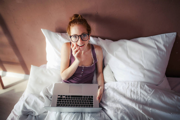 kobieta korzysta z laptopa leżąc w łóżku  - Zdjęcie, obraz