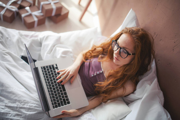 woman using laptop while lying in bed  - Φωτογραφία, εικόνα