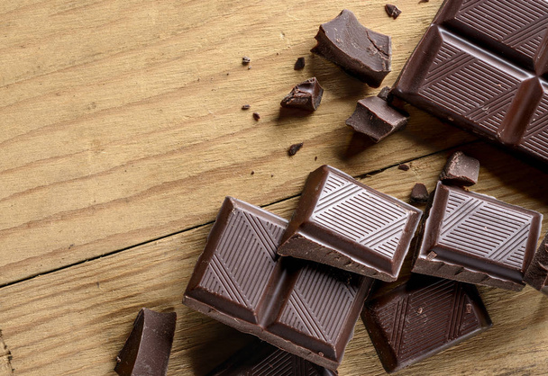 close up de pedaços de chocolate na velha mesa de madeira
 - Foto, Imagem