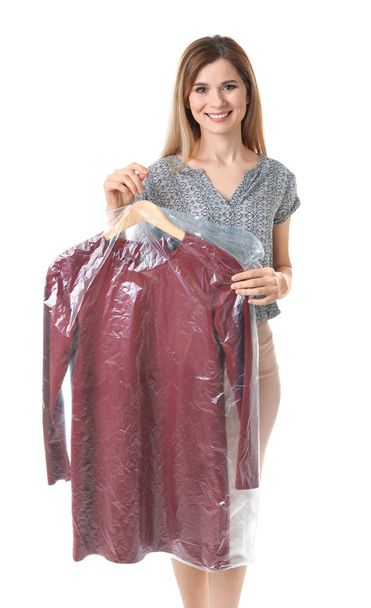 Young woman holding hanger with dress in plastic bag on white background. Dry-cleaning service - Foto, Imagen