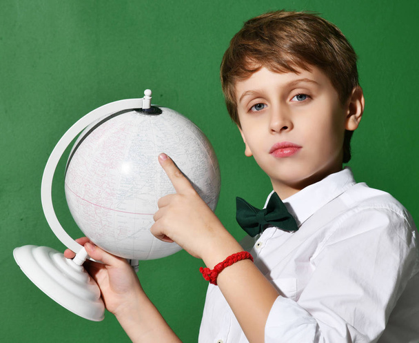 Cheerful school boy in white shirt holding globe in hands on green  - Foto, Imagem