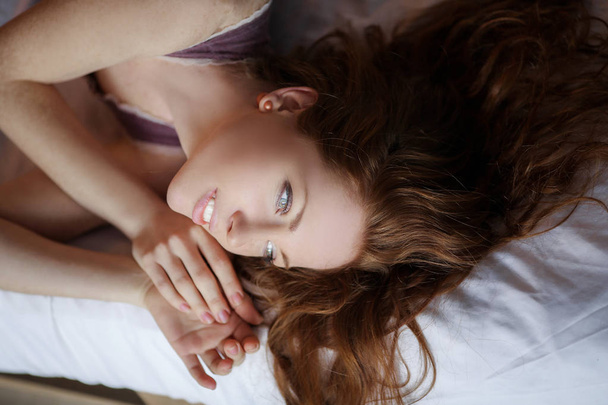close up portrait of beautiful red haired woman lying in bed  - Фото, изображение