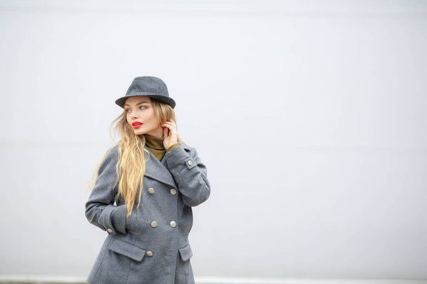 outdoor portrait of beautiful blonde woman wearing grey hat and coat  - Photo, image