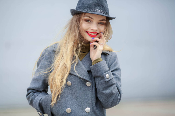 outdoor portrait of beautiful blonde woman wearing grey hat and coat  - Foto, Imagem