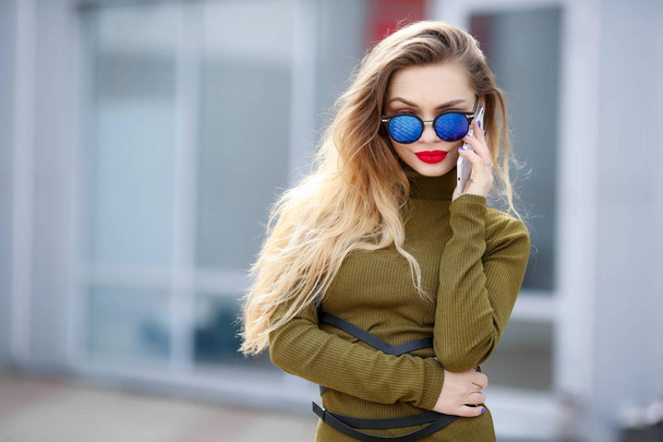 young beautiful woman posing outdoors wearing green dress and sunglasses  - Fotografie, Obrázek