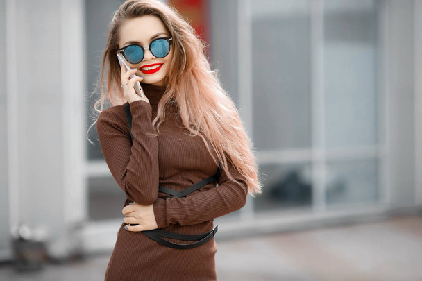 young beautiful woman posing outdoors wearing brown dress and sunglasses  - 写真・画像