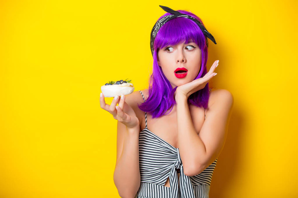 chica con el pelo morado sosteniendo un pastel de crema
 - Foto, imagen