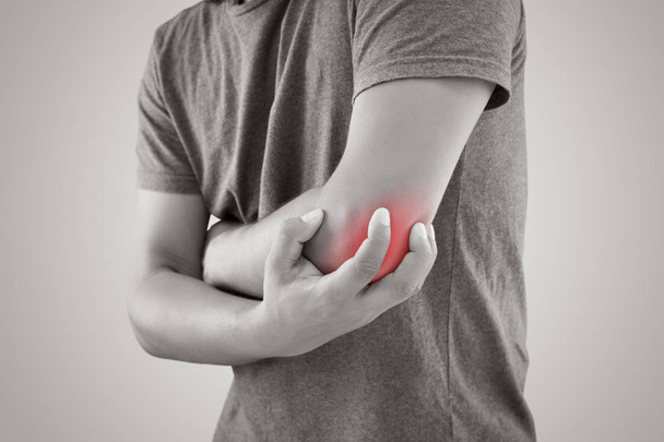 Homem asiático com dor no cotovelo contra fundo cinza
 - Foto, Imagem