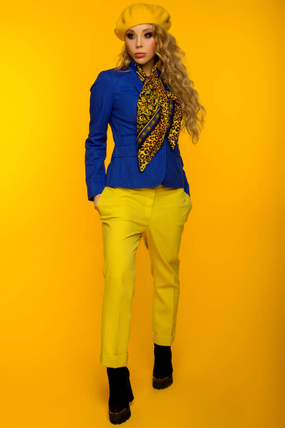 Modefoto. Blondine mit gelber Baskenmütze in blauer Jacke und gelbem Hemd - Foto, Bild