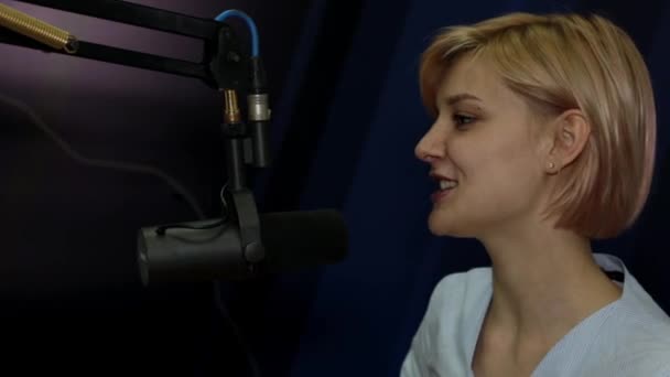 Nuori nainen DJ puhuu mikrofonilla studiossa radioasemalla
 - Materiaali, video