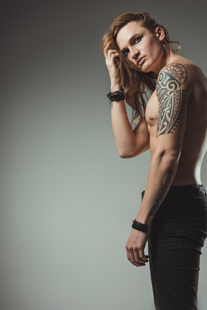 shirtless man with tattoo and long hair posing for fashion shoot, isolated on grey - Fotoğraf, Görsel