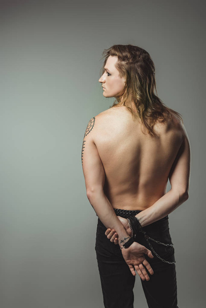 fashionable shirtless man with long hair posing in black jeans, isolated on grey - Fotoğraf, Görsel