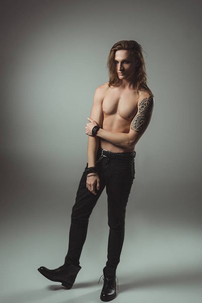 bel homme torse nu avec tatouage posant en jean noir, sur gris
 - Photo, image