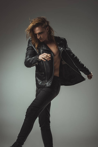shirtless man posing in black jeans and leather jacket, isolated on grey - Fotografie, Obrázek