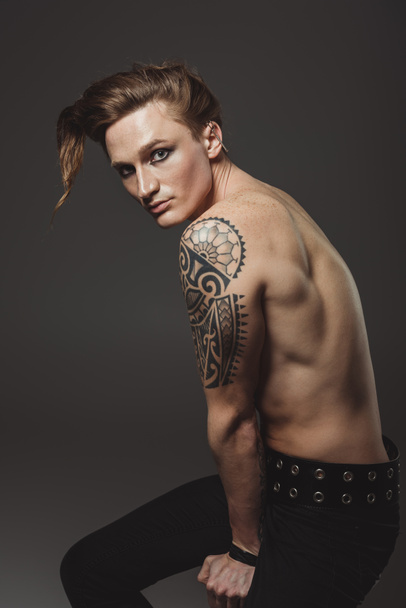 modèle masculin tatoué torse nu avec une coiffure étrange, isolé sur gris
 - Photo, image