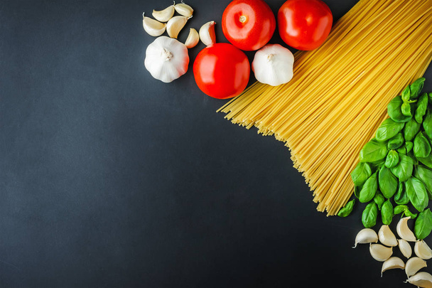 Pasta en ingrediënten voor koken op een donkere achtergrond met kopie ruimte - Foto, afbeelding