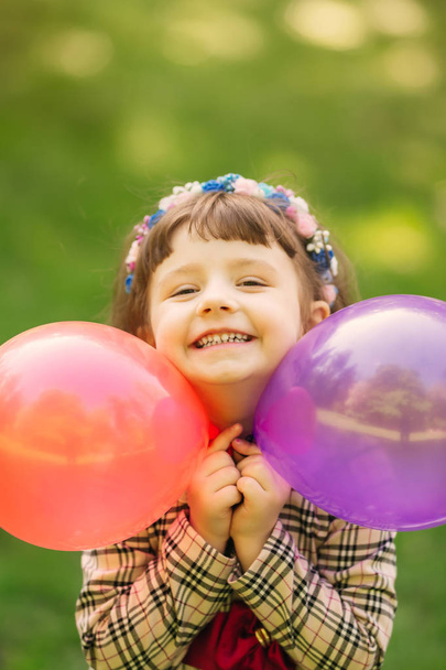 sincere smile of a little girl who holds the balloons in her han - Foto, imagen