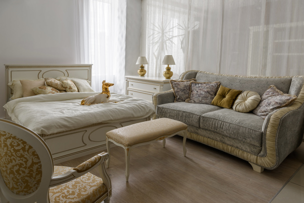 Kutya szobrocska ágyon fehér ágynemű, elegáns szobában - Fotó, kép