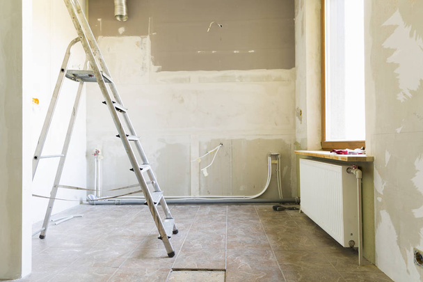 Sanierungskonzept für Eigenheime. Küche im Prozess der Reparatur und Renovierung. Leiter und Bauwerkzeug - Foto, Bild