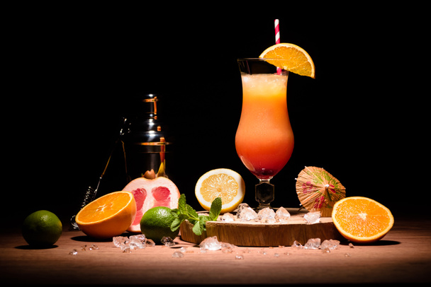 alcohol cocktail met sinaasappelsap op houten bord met fruit op tafel - Foto, afbeelding
