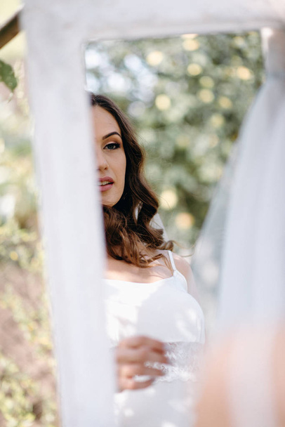 Closeup of bride looking in mirror in garden - Zdjęcie, obraz
