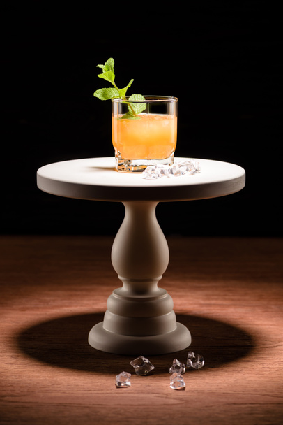 Alkoholcocktail mit Minze und Eiswürfeln auf Kuchenständer auf dem Tisch - Foto, Bild