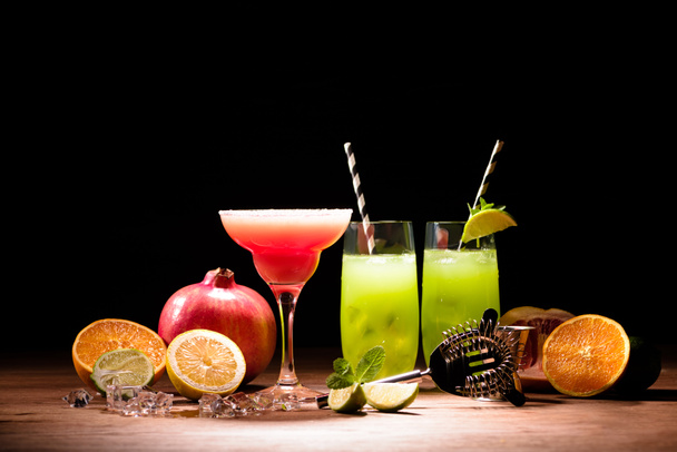 alcohol cocktails met limoen en granaatappel op tafel - Foto, afbeelding