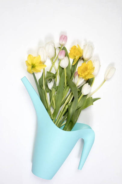 the Yellow rubber boots with a bouquet of flowers of yellow daffodils and white and pink tulips. Garden accessories. - Photo, image