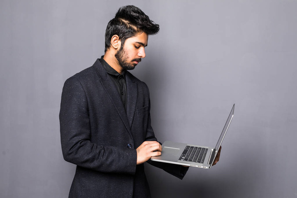 Muotokuva onnellinen intialainen liikemies käyttää kannettavaa tietokonetta harmaalla pohjalla
 - Valokuva, kuva