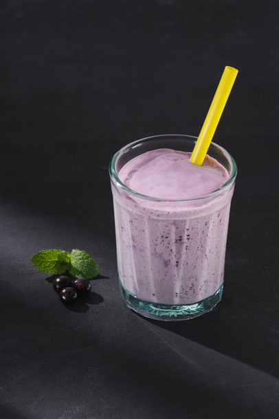 closeup shot of berry smoothie glass with drinking straw, currants and mint on table - Foto, immagini